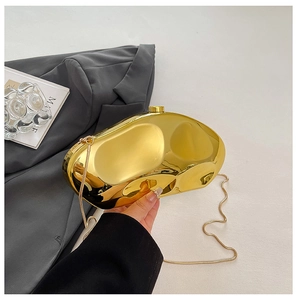 Detailed close-up of a golden pebble-shaped evening bag with a metallic mirror finish