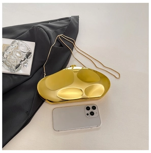 Detail of gold meteorite-shaped clutch with metal chain and smooth mirror finish