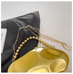 Macro detail of gold meteorite acrylic clutch with fluid lava texture and beaded handle