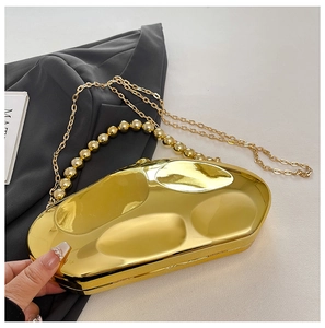 Detail of gold acrylic clutch bag with organic texture, bead handle, and chain strap
