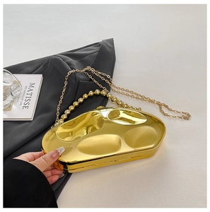 Detailed view of a gold geometric evening clutch bag with glossy metallic finish and chains