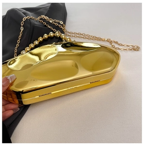 Close-up of golden irregular meteorite clutch with bead handle and chain strap