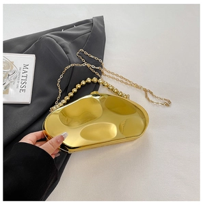 Detail of gold liquid metal evening clutch with beaded handle and chain on white texture