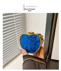 Close-up of heart-shaped blue sequin evening bag held by hand with gold chain