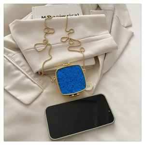 Detail of blue textured mini clutch with gold metal frame and thin bead chain