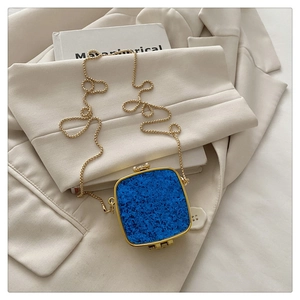 Detail of royal blue acrylic mini bag with grainy texture and golden metal frame