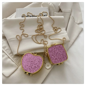 Detail of mini pink sequin jewelry bags with gold chains on a white blazer background