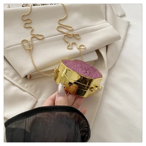 Detail of heart-shaped mini acrylic evening bag with purple glitter and gold chain