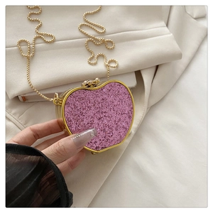Detail of pink glitter heart clutch bag with gold frame and chain strap accessory