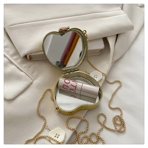 Detail of heart-shaped gold acrylic mini bag showing internal double-sided mirror