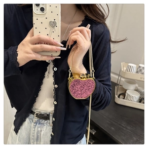 Close-up of bright pink sequin mini heart evening bag with gold metal frame and chain strap