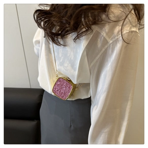 Close-up of pink glitter mini acrylic crossbody bag with gold chain on model back