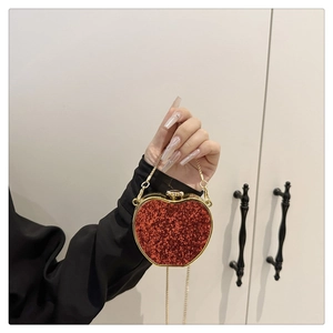 Close-up of heart-shaped red glitter evening bag with gold chain strap and metal clasp