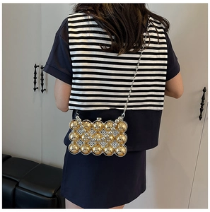 Detail of luxury acrylic evening bag with gold hemisphere beads and slim metal chain