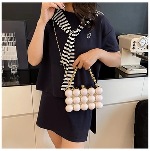 Detail of white acrylic pearl evening clutch with gold beaded handle and metal chain