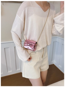 Détail du mini sac bandoulière rose en cuir verni avec nœud papillon et chaîne dorée