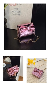 Détail du mini sac bandoulière en cuir verni rose avec grand nœud et chaîne dorée