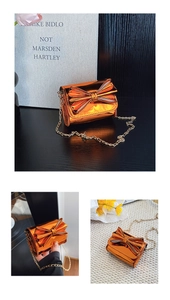 Détail du mini sac bandoulière orange métallisé avec nœud et fine chaîne dorée