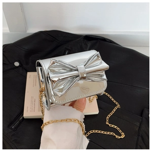 Détail du mini sac bandoulière argenté en cuir verni avec nœud et chaîne dorée
