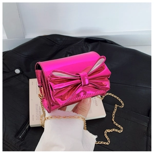 Détail du mini sac en cuir verni fuchsia avec nœud et bandoulière chaîne dorée