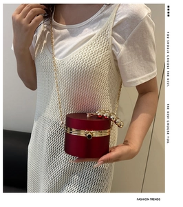 Detail of burgundy cylinder acrylic clutch with large gold bead handle and chain strap