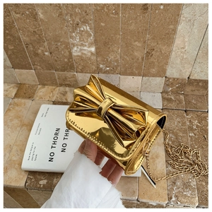 Détail du mini sac bandoulière doré effet miroir avec un grand nœud et une chaîne dorée