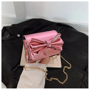 Gros plan sur le sac bandoulière rose métallisé avec nœud et chaîne dorée élégante