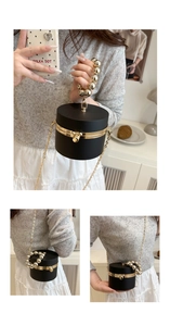 Detail of cylindrical black acrylic evening bag with gold trim and beaded handle
