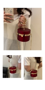 Macro detail of wine red cylindrical evening bag with gold bead handle and chain strap