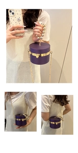 Detailed view of dark purple cylindrical acrylic evening bag with gold beaded handle