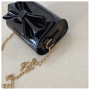 Détail du mini sac en cuir verni brillant avec grand nœud et chaîne dorée