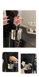 Detailed view of silver metallic cylindrical clutch bag with beaded handle and chain strap