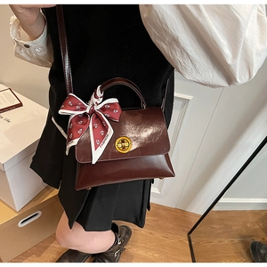 Close-up of vintage dark burgundy handbag with silk scarf handle and metal ring lock