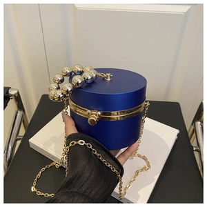 Detail of royal blue cylindrical acrylic evening bag with silver beaded handle and gold chain