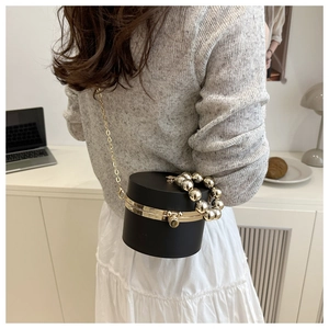 Fashionable black acrylic cylindrical clutch bag with gold round handle and metal chain strap