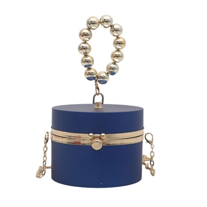 Detail of navy blue cylindrical evening bag with gold beaded handle and metal chain strap