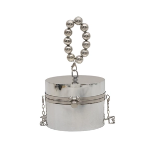 Detailed macro view of silver metallic cylindrical handbag with beaded ring handle and clasp