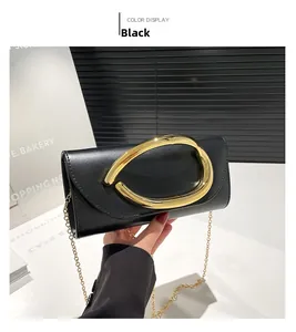 Dettaglio della pochette in pelle nera con manico dorato e tracolla a catena in metallo