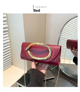 Dettaglio di una pochette da sera rossa con grande fibbia in metallo dorato e catenina