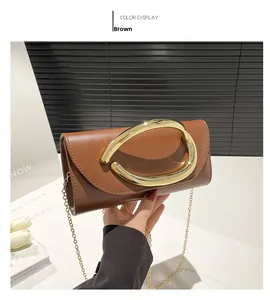 Dettaglio di una pochette in pelle marrone con chiusura scultorea dorata e catena