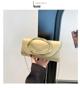 Dettaglio di una pochette da sera oro con grande manico ovale in metallo e catena