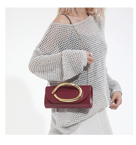 Dettaglio pochette da sera bordeaux con fibbia dorata e tracolla a catena in metallo