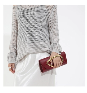 Elegante pochette bordeaux con manico dorato a forma di occhio su gonna di seta bianca
