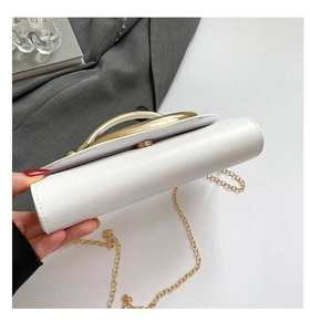 Dettaglio clutch in pelle bianca con manico in metallo dorato e fibbia magnetica