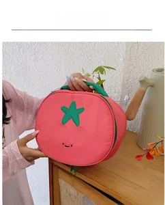 Detail of cute tomato-shaped nylon handbag with green star leaves and black smiley embroidery