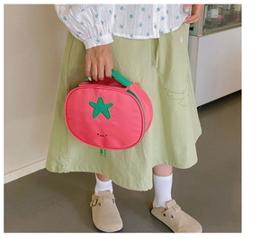 Close-up of cute tomato-shaped pink nylon makeup bag with green leaves and handle detail