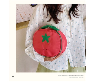 Detail of red nylon makeup bag featuring a green star and embroidered smiley face