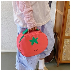 Creative tomato shaped nylon bag with green handles shown in a lifestyle home setting