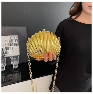 Detail of shell-shaped metallic gold clutch with elegant round link chain strap