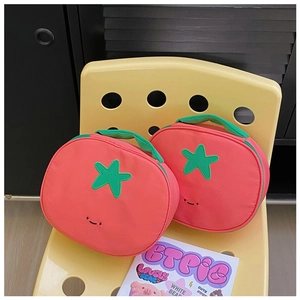 Detail of tomato-shaped nylon storage bags with green handles and cute smiling face design
